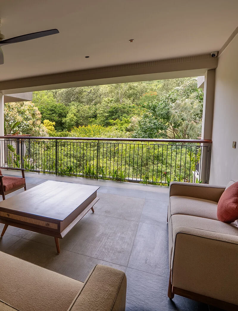 A living room with a balcony over the trees